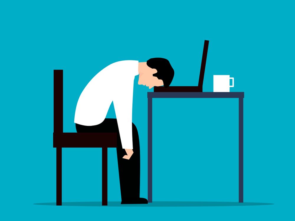 Trabalhador cansado caído sobre o computador, pois não teve autocuidado.
